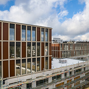 Dank der guten Fortschritte beim Neubau der SteinPark-Schulen kann jetzt auch die glänzende Klinkerfassade mit den Glas-Beton-Elementen bewundert werden. (Drohnenfoto: F.J. Kirmaier/das produktionshaus)