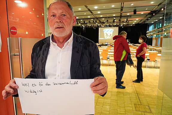 Planungsreferent Hans Hölzl hält ein Schild mit der Aufschrift: "weil es für den Zusammenhalt wichtig ist."