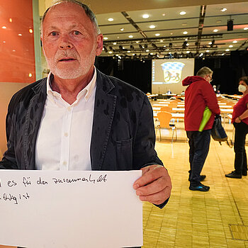 Planungsreferent Hans Hölzl hält ein Schild mit der Aufschrift: "weil es für den Zusammenhalt wichtig ist."