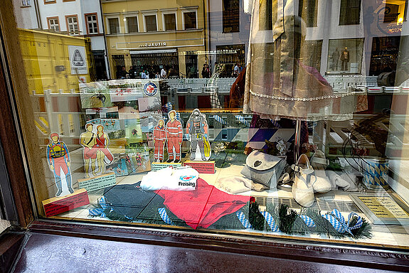 Pappfiguren und Fotos sowie Wasserwacht-Shirts zwischen Trachtenkleidung