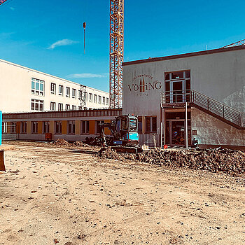Das Foto zeigt von außen die beiden Bestandsgebäude der Schule und davor die Baustelle.