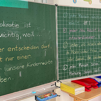 Tafel mit Schrift: Demokratie ist mir wichtig, weil... 1 jeder entscheiden darf, nicht nur einer. 2 wir unsere Kinderrechte haben, 3 jeder Mensch gleich viel zählt...