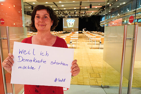 Sozialreferentin Dr. Charlotte Reitsam, hält ein Schild mit der Aufschrift: "weil ich Demokratie stärken möchte!"