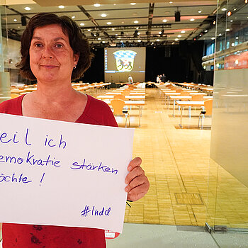 Sozialreferentin Dr. Charlotte Reitsam, hält ein Schild mit der Aufschrift: "weil ich Demokratie stärken möchte!"