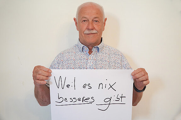 Stadtratsmitglied Benno Zierer. Foto: Stadt Freising Ein Mann in einem weißen Hemd zeigt ein Schild mit der Aufschrift "weil es nichts besseres gibt"