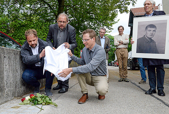 OB Tobias Eschenbacher, Geschichtsreferent Guido Hoyer und Oberstudienrat Andreas Decker (v.l.) enthüllen die kleine Gedenktafel. Komplett finanziert hat Fritz Schulte (rechts) den Stolperstein. (Foto: Stadt Freising)