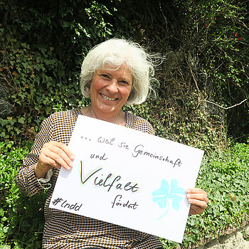 Sylvia Thalhammer hält ein Schild mit der Aufschrift: "...weil sie (Demokratie) Gemeinschaft und Vielfalt fördert." 