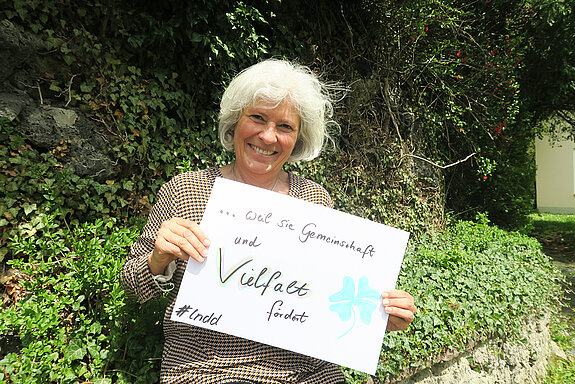 Sylvia Thalhammer hält ein Schild mit der Aufschrift: "...weil sie (Demokratie) Gemeinschaft und Vielfalt fördert." 