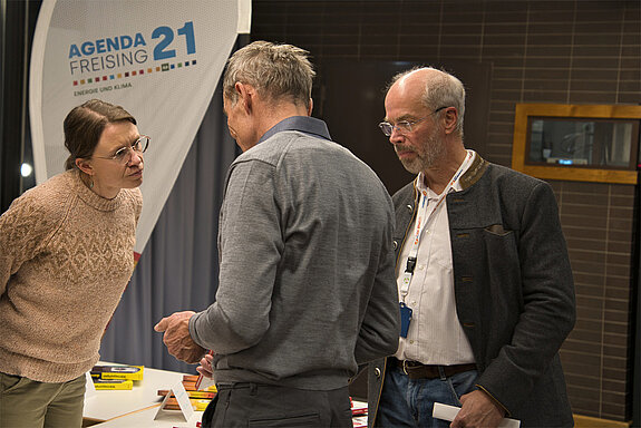 Daniela Voss und Bertram Hock beraten am Stand der Agenda21 Energie und Klima. Foto: Hendrik Edelhoff Eine Frau und ein Mann im Gespräch mit einem Mann, der den Rücken zur Kamera wendet. Im Hintergrund eine Beachflag "Agenda21"