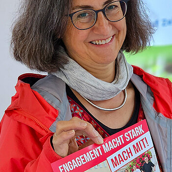 Eine Frau mit dem Plakat der Aktionswoche in rot, blau, weiß "Engagement macht stark"