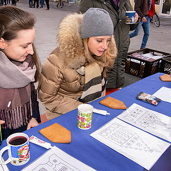 Studium von Silhouetten der Freisinger Altstadt, die nun mit Zuckermasse auf den Lebkuchen gezeichnet werden sollen - oder einfach das Haus essen? (Foto: Stadt Freising)
