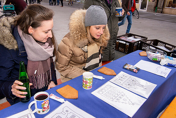 Studium von Silhouetten der Freisinger Altstadt, die nun mit Zuckermasse auf den Lebkuchen gezeichnet werden sollen - oder einfach das Haus essen? (Foto: Stadt Freising)