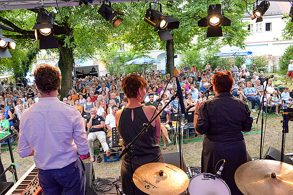 Schöner Moment für Bürgermeisterin Eva Bönig, Kulturreferentin Susanne Günther und Musikschulleiter Odilo Zapf: Der Eröffnungsabend des Sommer Wunders ist ausverkauft und die Stimmung im Amtsgerichtsgarten einfach zauberhaft. (Foto: Stadt Freising)