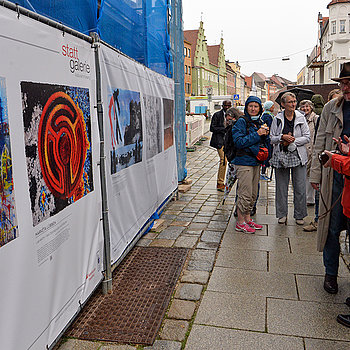 Farbenprächtig schmücken die mit Werken Freisinger Künstler*innen bedruckten Bauzaunbanner die eingerüstete Rathaus-Fassade. (Foto: Stadt Freising)