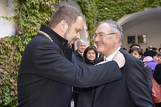 OB Eschenbacher steckt dem neuen Träger der Bürgermedaille, Weihbischof Bernhard Haslberger (re.) die goldene Nadel ans Revers.