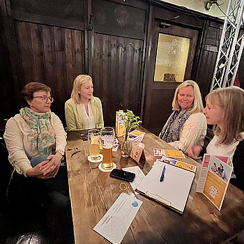vier Frauen unterhalten sich an einem Tisch