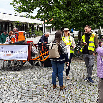 Ein zum Kaffeestand umgebautes Fahrrad und mehrere Menschen darum herum