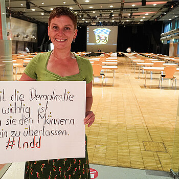 Susanne Günther hält in der Luitpoldhalle ein Schild mit der Aufschrift: "...weil die Demokratie zu wichtig ist, um sie den Männern allein zu überlassen." #lndd
