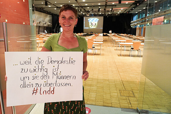 Susanne Günther hält in der Luitpoldhalle ein Schild mit der Aufschrift: "...weil die Demokratie zu wichtig ist, um sie den Männern allein zu überlassen." #lndd