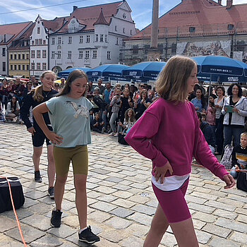 mehrere Mädchen in sportlichem Outfit gehen vor eine Menschenmenge 