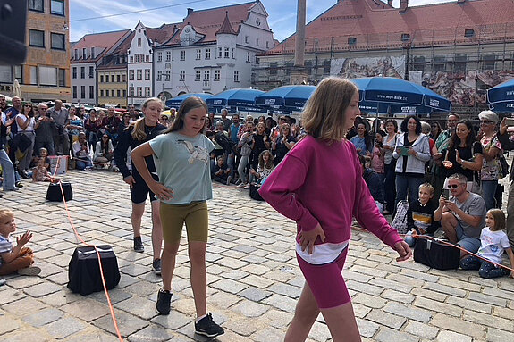 mehrere Mädchen in sportlichem Outfit gehen vor eine Menschenmenge 