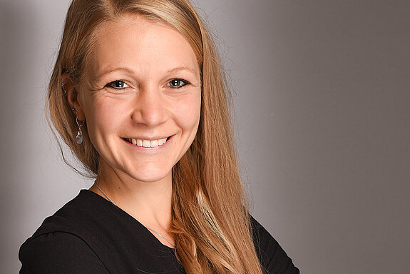 Blonde, langhaarige Frau lächelt freundlich in die Kamera