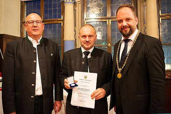 OB Tobias Eschenbacher zeichnet Martin Heilmeier (Mitte) aus. (Foto: Stadt Freising)