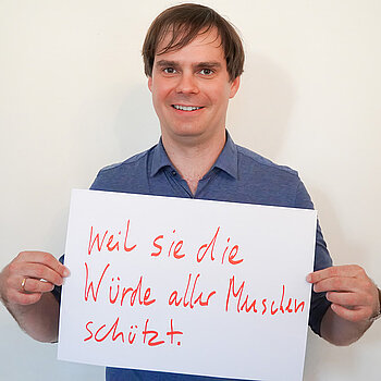 Stadtratsmitglied Dr. Andreas Mehltretter. Foto: Stadt Freising Ein Mann in einem blauen Hemd zeigt ein Schild mit der Aufschrift "weil sie die Würde der Menschen schützt"