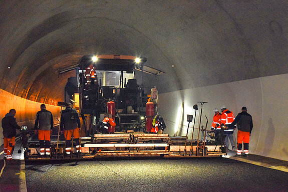 Alle Hände voll zu tun haben die Bauarbeiter am Asphaltfertiger - und neben dem Lärm ist es hier richtig heiß, weil der Mastix mit 180 Grad angeliefert wird. (Foto: Stadt Freising)