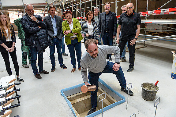 OB Tobias Eschenbacher legt die Zeitkapsel in den Bodenschacht. (Foto: Stadt Freising)