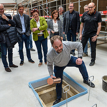 OB Tobias Eschenbacher legt die Zeitkapsel in den Bodenschacht. (Foto: Stadt Freising)