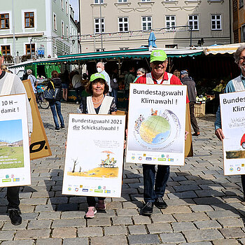 Vier Menschen mit Sandwich-Plakaten für mehr Klimaschutz auf dem Freisinger Wochenmarkt.