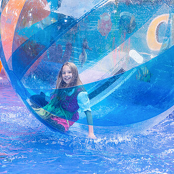 Beim "Waterball" ist man/frau im Ball und versucht, aufrecht stehen zu bleiben - den Kindern gelingt das insgesamt ganz gut. (Foto: Stadt Freising)