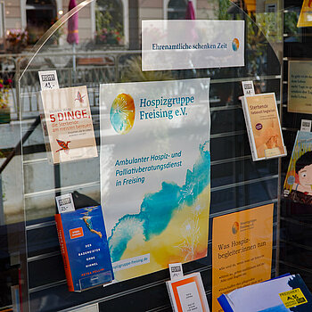 ein Plakat in Gelb und Türkis in der Mitte, darum viele Bücher.
