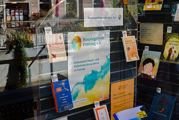 ein Plakat in Gelb und Türkis in der Mitte, darum viele Bücher.