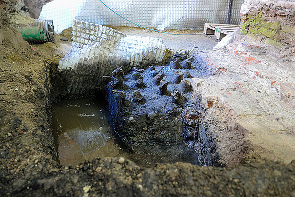 Für die flächendeckende Entwässerung muss eine Drainage eingebracht werden - und bei dieser Gelegenheit bietet sich ein Blick auf die historische Verankerung des Gebäudes mit Eichenpfählen. (Foto: Stadt Freising)