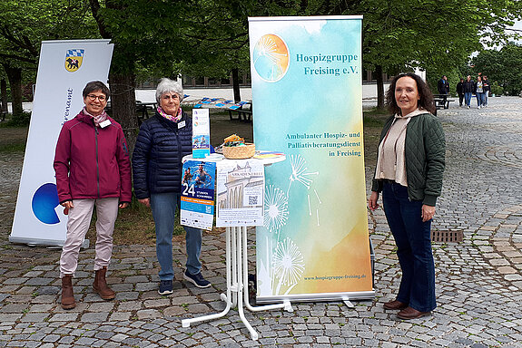 Drei Frauen neben einem Rollup und eine Stehtisch