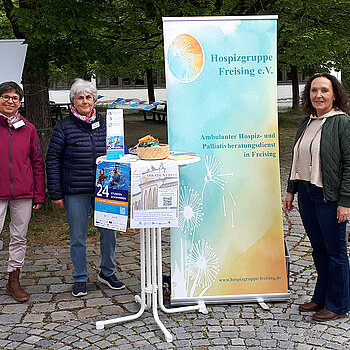 Drei Frauen neben einem Rollup und eine Stehtisch