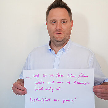 Stadtratsmitglied Robert Weller. Foto: Stadt Freising Ein Mann in einem weißen Hemd zeigt ein Schild mit der Aufschrift "weil ich ein freies Leben führen möchte und mir die Meinungsfreiheit wichtig ist. Engstirnigkeit war gestern!"