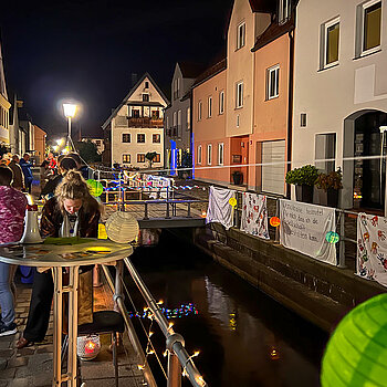 Transparente und bunte Lampions an der Brüstung der Moosach in der Fischergasse bei Nacht.