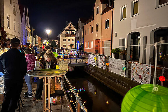 Transparente und bunte Lampions an der Brüstung der Moosach in der Fischergasse bei Nacht.