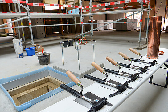 Es ist angerichtet: Kelle und Hammer liegen bereit, rechts die Zeitkapsel, die im vorbereiteten Schacht  eingemauert wird. (Foto: Stadt Freising)   