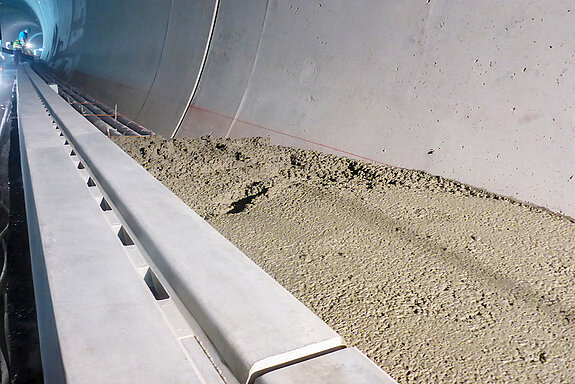 Tunnelbau Westtangente Freising: Ausbauarbeiten im Bergmännischen Tunnel mit Schlitzrinne und Kabelleerrohren im Bereich der Notgehwege