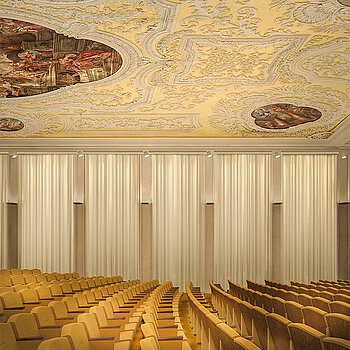 Eine Visualisierung zeigt, wie der Theatersaal mit der historischen Decke, eleganten Vorhängen und stimmungsvoller Beleuchtung aussehen wird. (Lichtplanung: Lichtlauf, Architekten: Wollmann und Mang, Bildbearbeitung: Nora Walter images)