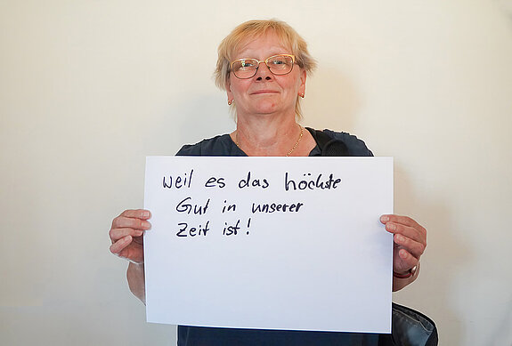 Stadtratsmitglied Johanna Hiergeist. Foto: Stadt Freising Eine Frau in einem blauen T-Shirt zeigt ein Schild mit der Aufschrift: "weil es das höchste Gut in unserer Zeit ist!
