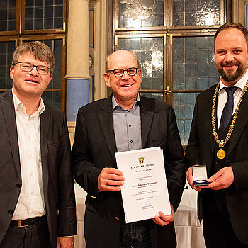 OB Tobias Eschenbacher zeichnet Nikolaus Stommel (Mitte) aus. (Foto: Stadt Freising)