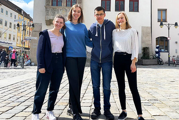 drei junge Frauen und ein junger Mann auf dem Marienplatz vor dem Freisinger Rathaus