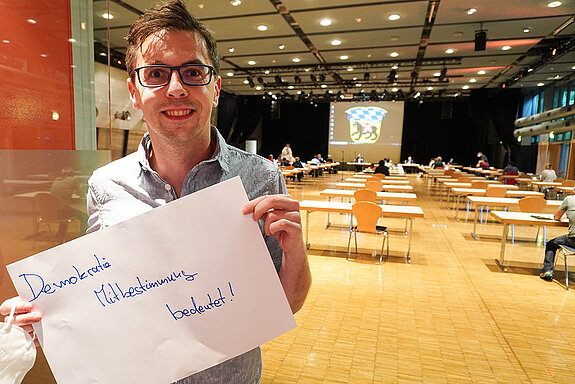 Stadtrat Dr. Jens Barschdorf hält ein Schild mit der Aufschrift: "Demokratie Mitbestimmung bedeutet!"