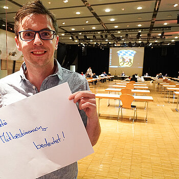 Stadtrat Dr. Jens Barschdorf hält ein Schild mit der Aufschrift: "Demokratie Mitbestimmung bedeutet!"