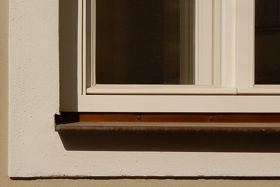 Detailausschnitt mit Fasche und einem Fenster mit konstruktivem Wetterschutzschenkel